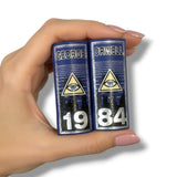 Two miniature books titled '1984' by George Orwell held in a hand against a white background.