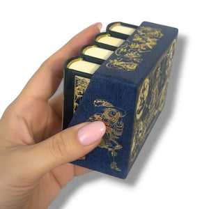 Hand holding a decorative blue box with gold designs containing white items. Gulliver's Travels