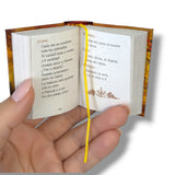 Hand holding a small open book with visible text and decorative cover.Sueño de una noche de Verano William Shakespeare