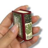 Hand holding a miniature book with decorative cover. the marriage of cupid and psyche