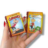 Two small books with cartoon character covers held by a hand on a white background Condorito