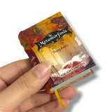 Miniature book titled 'La Metamorfosis' held by a hand on a white background