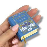 Hand holding a miniature book with decorative cover El Retrato de Dorian Gray