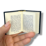 Hand holding a small open book with text on a white background.Gulliver's Travels