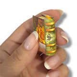 Hand holding a small, intricately designed product with visible branding on a white background