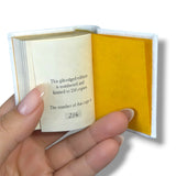 Hand holding a small book with text on a white background
