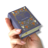 Hand holding a miniature book titled 'Mansfield Park' by Jane Austen against a white background