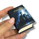 Miniature book titled 'Frankenstein' held by a hand with a dark cover design.