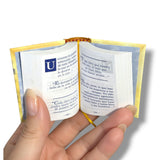 Hand holding a small open book with text on a white background. Jose Marti