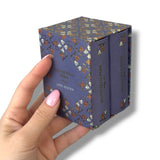 Hand holding a purple book with floral design and 'Mansfield Park' by Jane Austen text.