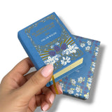 Decorative book with floral design held by a hand on a white background. El Retrato de Dorian Gray