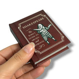 Miniature book titled 'Shakespeare's Guide' held in a hand against a white background