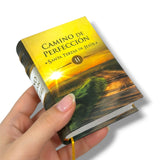 Book titled 'Camino de Perfeccion' held by a hand on a white background