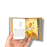 Ganesh. Hand holding an open book with illustrations and text on a white background