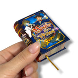 Hand holding a small book titled 'Magia Para Niños' against a white background