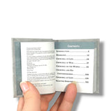 winston Churchill Hand holding a miniature book with an open page showing a table of contents.