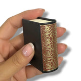 Hand holding a small, ornate box with gold floral patterns on a white background Rubaiyyat