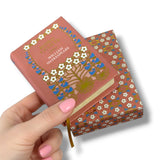 Decorative book with floral patterns held by a hand on a white background. Romeo y Julieta