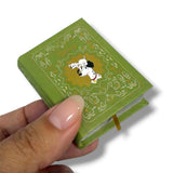Green miniature book with a dog illustration held by a hand on a white background 102 dalmatas