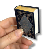 Miniature book titled 'Short Stories' by Nathaniel Hawthorne held in a hand against a white background
