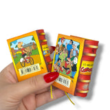 Hand holding two colorful books with cartoon characters on a white background. Condorito