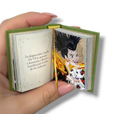 Miniature book open in a hand with illustrations and text on a white background. 102 Dalmatas
