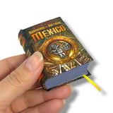 Hand holding a decorative book titled 'México' with intricate designs on the cover.