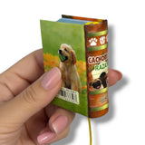 Hand holding a small book-shaped product with dog-themed design Cachorros Razas